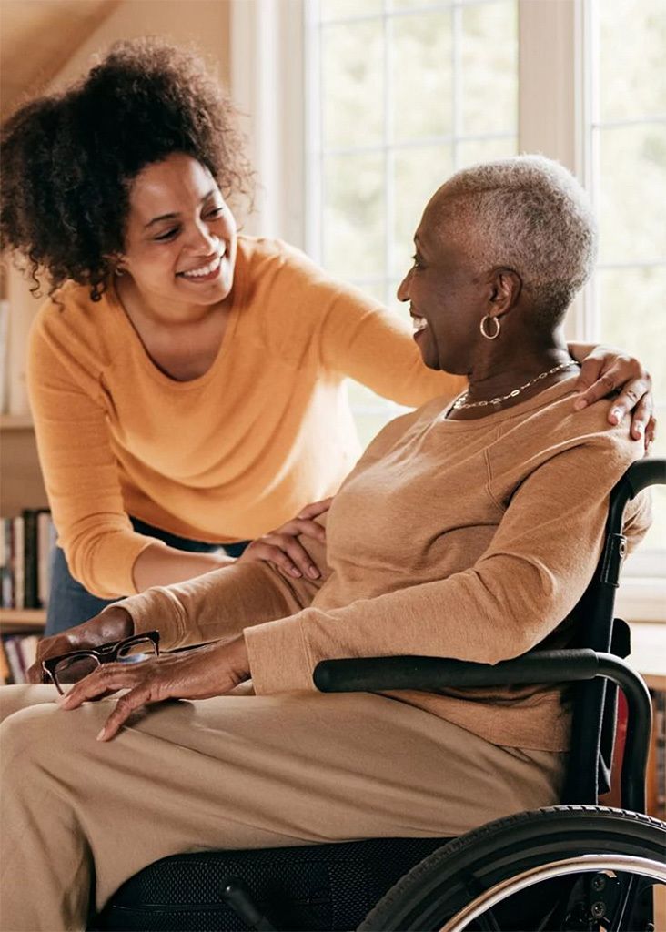 A carer supporting a senior woman in a wheelchair